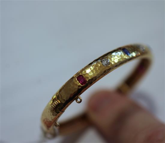 A planished 18ct gold, ruby sapphire and diamond hinged bangle, gross weight 20.4 grams.